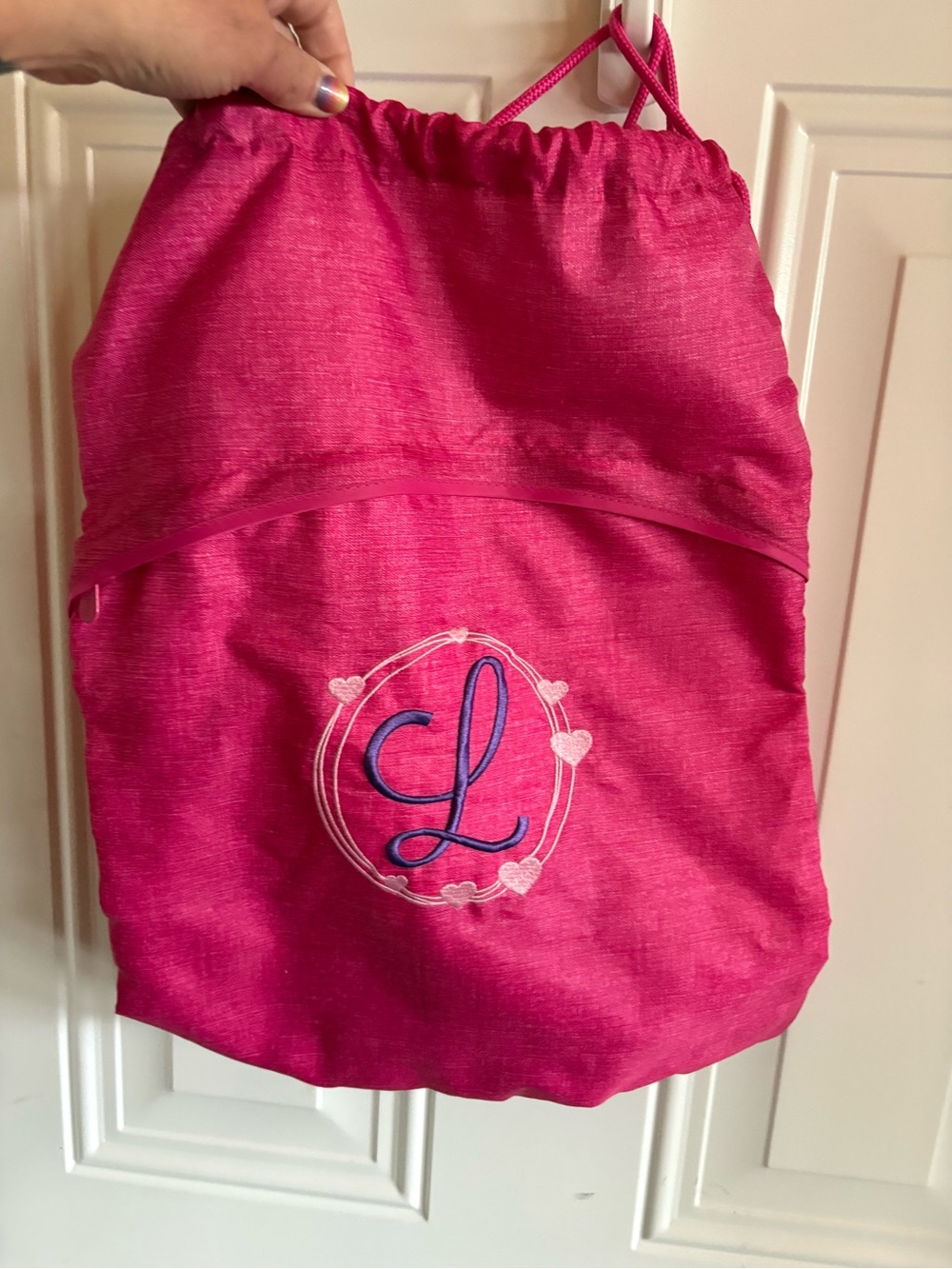 Cute personalized drawstring backpack in a vibrant pink fabric, letter L